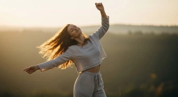 A woman dancing freely in soft morning light, surrounded by open space.
